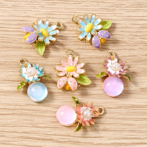 Détail de pendentifs marguerites et coccinelles avec perles en verre sur fond de bois
