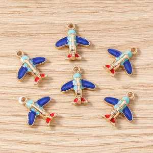 Detailed view of six colorful airplane charms with blue and red enamel on a wood surface