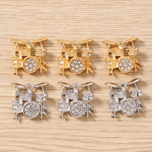 Makro-Detail von trommelförmigen Schmuckanhängern mit funkelnden Strasssteinen in Gold und Silber