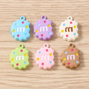 Gros plan de pendentifs biscuits colorés en résine avec lettre M pour création de bijoux