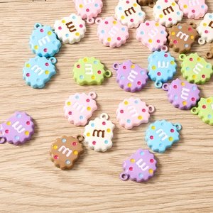Détail macro de breloques biscuits en résine colorée avec lettre M et boucle de suspension