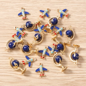 Blue airplane and globe alloy charms set for DIY jewelry making on wooden background