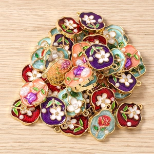 Makroansicht verschiedener Emaille-Blumenanhänger mit Goldrahmen und Perlenverzierung