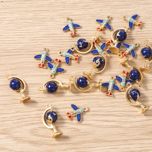 Detailed view of blue enamel airplane and globe charms for DIY jewelry making