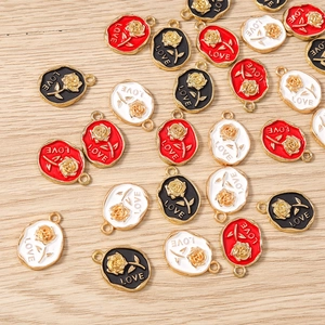 Close-up of vintage oval enamel rose pendants with gold LOVE text for DIY jewelry