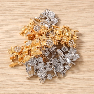 Makro-Detail von trommelförmigen Legierungsanhängern mit weißen Strasssteinen in Gold