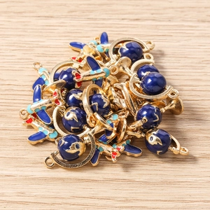 Macro view of blue enamel airplane and globe charms for DIY jewelry making accessories