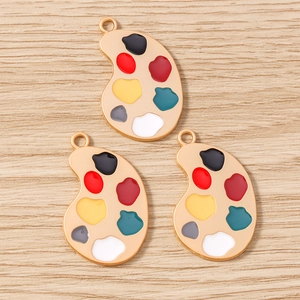 Vue rapprochée de pendentifs palette de peinture émaillée sur un fond en bois clair