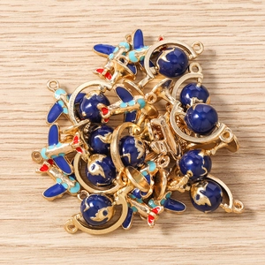 Detail of golden airplane and globe alloy charms with blue enamel for DIY jewelry making