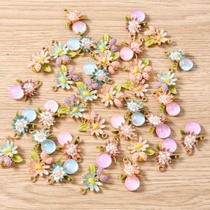 Détail de breloques DIY avec marguerites émaillées, perles et pendentifs mats colorés