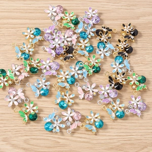 Vue détaillée de breloques colorées en émail en forme de fleur et papillon avec strass
