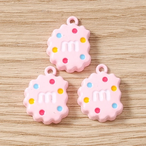 Détail de breloques biscuits en résine rose avec lettre m pour la création de bijoux DIY