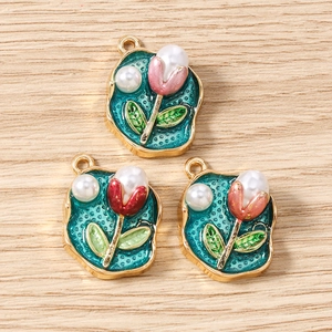 Detailansicht der goldenen Tulpen-Anhänger mit Emaille-Inlay und Perlenakzenten