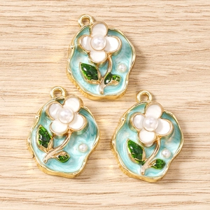 Detail von floralen Emaille-Anhängern mit Goldrand und Perlenmitte für DIY-Schmuck