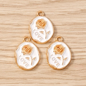 Detailed macro of golden rose oval charms with white enamel and LOVE engraving
