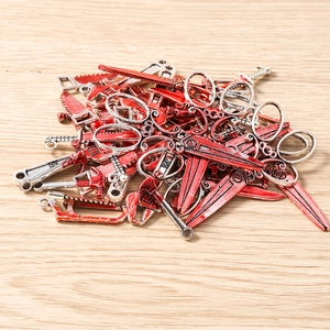 Detailed view of bloody horror metal charms featuring saws, scissors, and tools