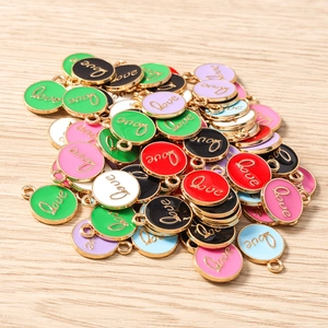 Macro detail of colorful enamel Love charms with gold metal edges for DIY jewelry making