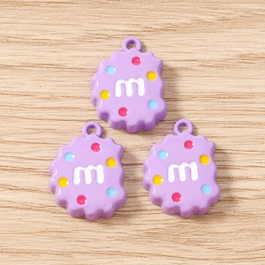 Détails de trois breloques biscuits violets en résine avec lettre m et points colorés