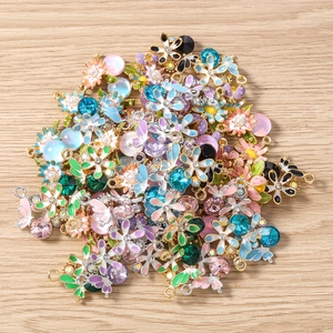 Vue rapprochée de breloques fleurs en émail coloré avec strass sur fond de bois clair