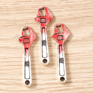 Macro detail of miniature wrench charms with red accents and RF engraving for DIY jewelry