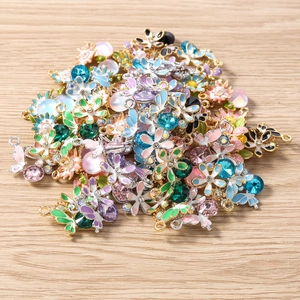 Vue détaillée de breloques en émail coloré fleurs et papillons pour bijoux DIY