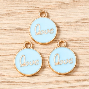 Macro shot of three round light blue enamel Love pendants with gold plating for DIY jewelry