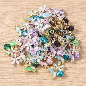 Vue détaillée de pendentifs fleurs et ailes en émail coloré avec des strass étincelants
