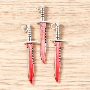 Macro detail of alloy bloody knife pendants with silver handles and red blades