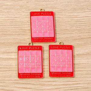 Detailansicht der roten und rosa Puzzle-Anhänger aus Legierung mit goldfarbenen Schlaufen