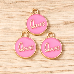Detailed macro view of three pink enamel Love round charms with gold edges for DIY jewelry
