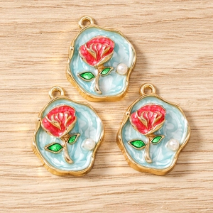 Details von Rosen-Emaille-Anhängern mit Goldrand und kleiner Perle auf Holzgrund