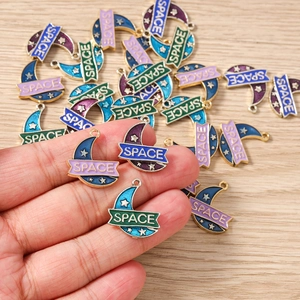 Detailed macro shot of enamel moon pendants with SPACE lettering for DIY jewelry making