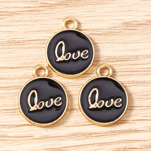 Detail of round gold-rimmed Love pendants with black enamel and calligraphy for DIY jewelry