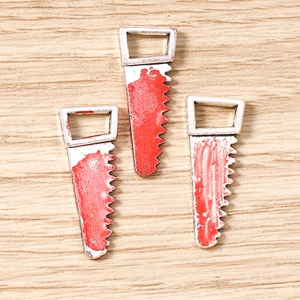 Detailed macro view of three silver alloy bloody saw pendants for DIY Halloween jewelry