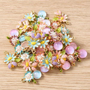 Détails de breloques marguerites en émail pastel avec perles sur fond en bois naturel