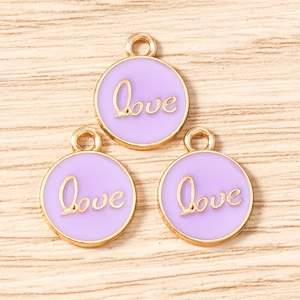 Macro detail of round purple enamel Love charms with gold metal edges for DIY jewelry
