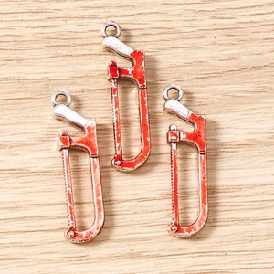 Macro shot of silver metal saw pendants with bloody red splatters on wood background