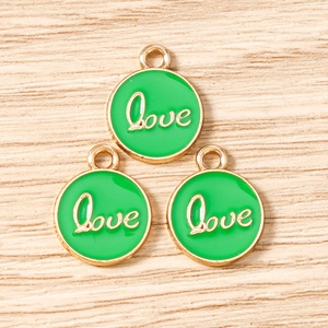 Detailed macro view of green enamel Love charms with gold metal edges and hanging loops