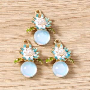 Détail de pendentifs floraux avec perles et globes bleus sur fond de bois clair