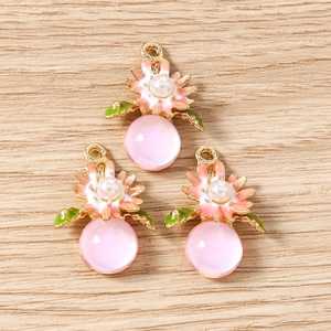 Détail de breloques fleurs en émail rose avec perles et billes de résine translucide