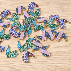 Detailed macro view of enamel moon charms with stars and Space lettering for DIY jewelry
