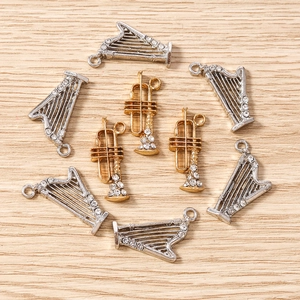 Détail de breloques en alliage harpe argentée et trompette dorée avec strass brillants