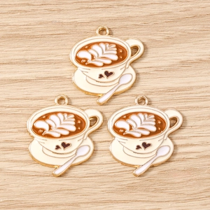 Dettaglio di ciondoli a tazza di caffè con latte art a cuore su legno chiaro