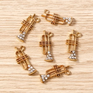 Détails de six pendentifs trompette dorés avec cristaux sur fond de bois