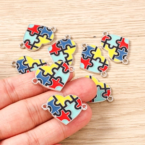 Detail of colorful puzzle heart charms for DIY jewelry making on a wooden background