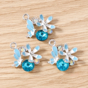 Vue détaillée de trois pendentifs papillon et fleur bleus avec émail et strass étincelants