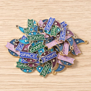 Macro detail of moon and star enamel pendants with SPACE text for jewelry making