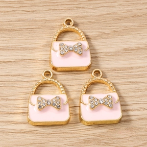Detailed view of pink enamel handbag charms with crystal bows and gold alloy plating