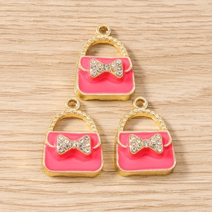 Macro shot of three pink handbag pendants with rhinestone bows for DIY jewelry making