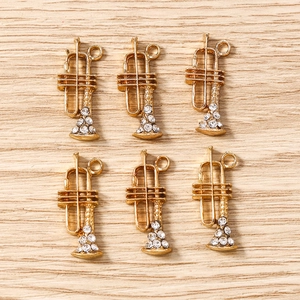 Détail de six pendentifs trompette dorés avec cristaux pour la création de bijoux DIY